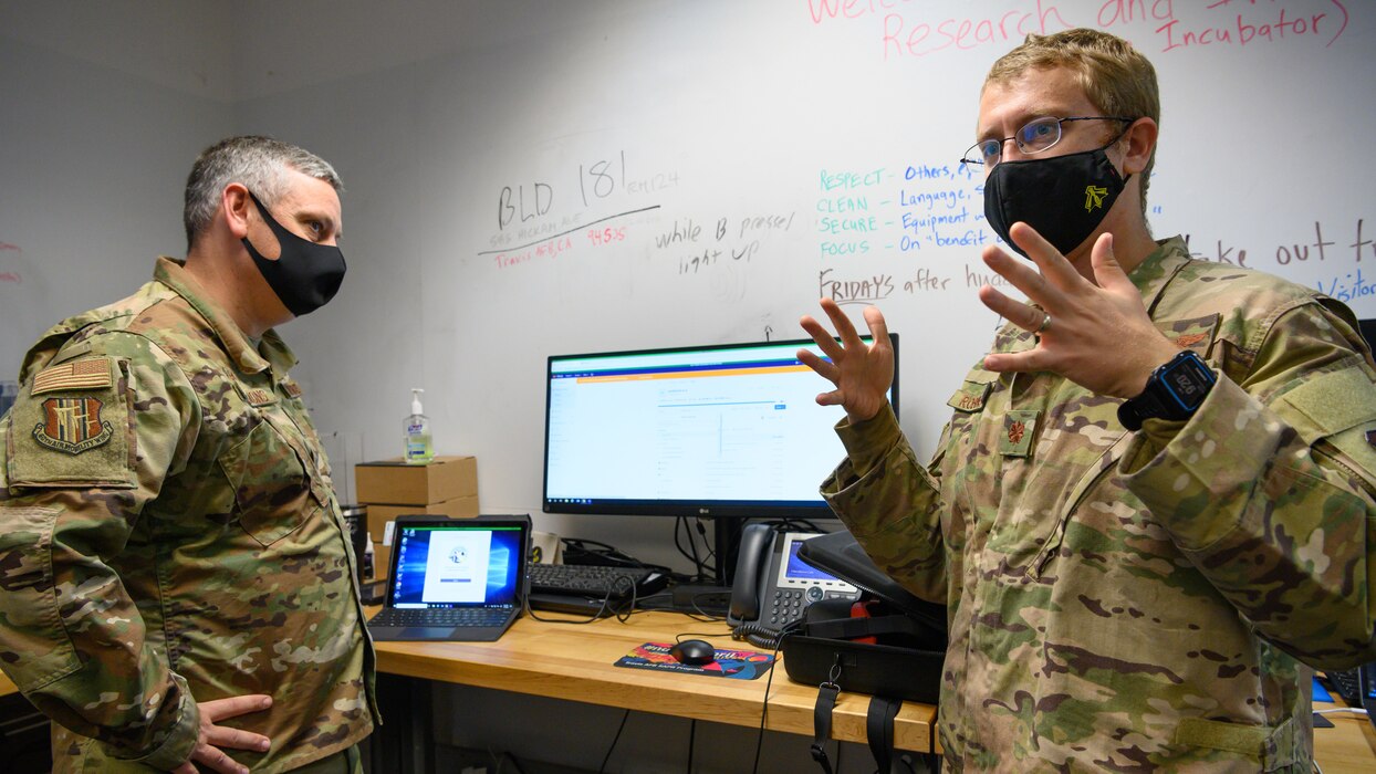 U.S. Air Force Maj. Eric Robinson, right, Phoenix Spark software lead, discusses innovation to Col. Corey Simmons, 60th Air Mobility Wing commander, during Leadership Rounds Nov. 6, 2020, at Travis Air Force Base, California. Robinson explained how the Puckboard is used; a new system utilized by 2500 Mobility Air Forces users for collaborative and mobile flight scheduling. The Leadership Rounds program provides 60th AMW leadership an opportunity to interact with Airmen and get a detailed view of each mission performed at Travis AFB. (U.S. Air Force photo by Chustine Minoda)