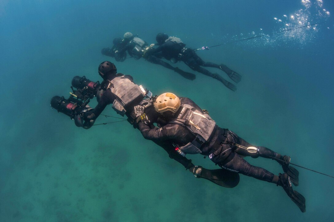 Two pairs of sailors use a driving device while tandem diving.