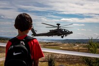 A young boy watches as an AH-64D Apache Longbow Helicopter assigned to the 1st Battalion, 3rd Aviation Regiment (Attack Reconnaissance), 12th Combat Aviation Brigade, flies overhead during the Viper Battalion family day event at Grafenwoehr Training Area, Germany, August 6, 2022. (U.S. Army photo by Staff Sgt. Preston Malizia)