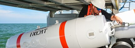 Deckhand Spencer Sharpe lays inert training mine-shapes for the Rim of the Pacific exercise.