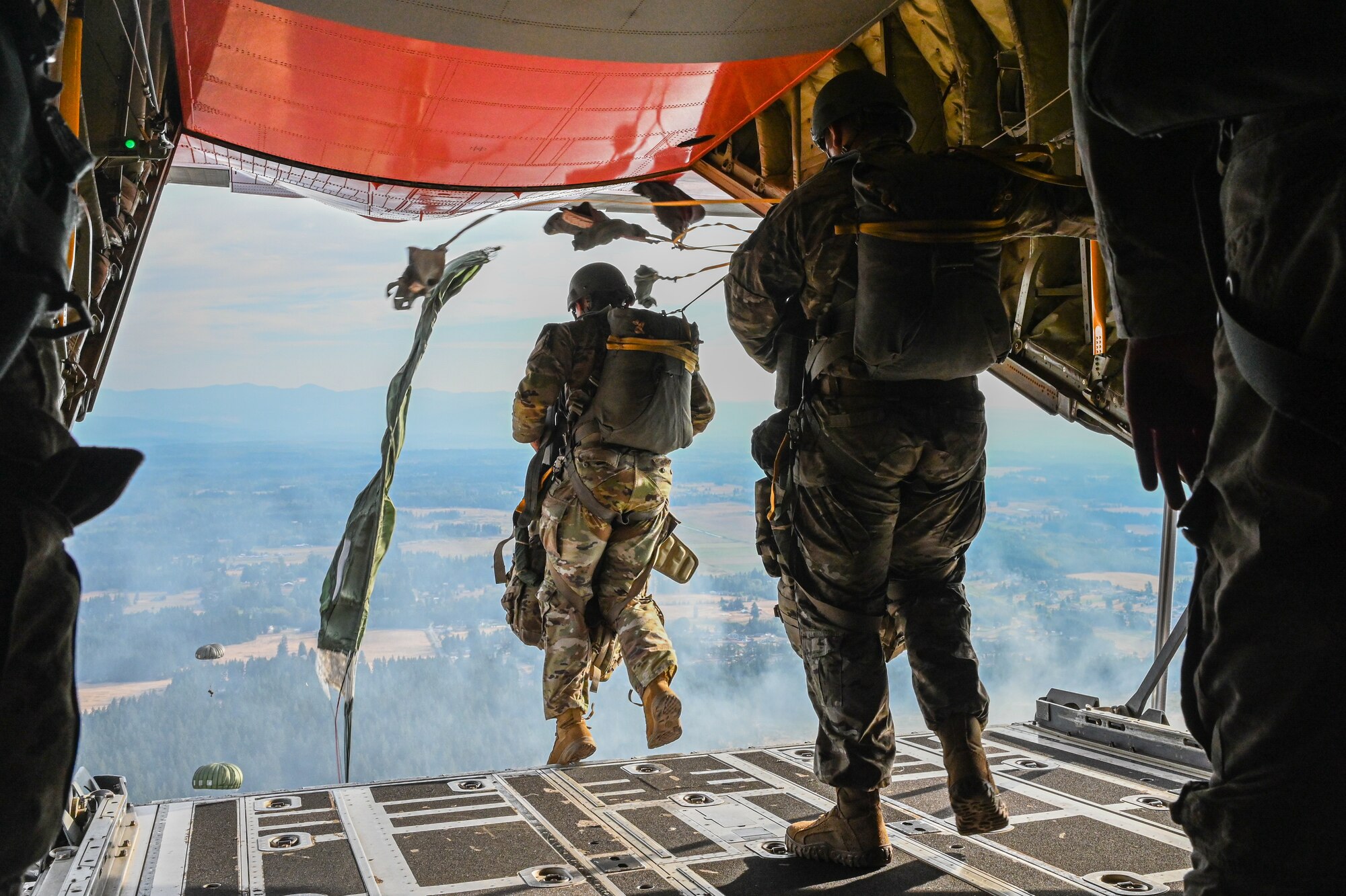 Paratroopers jump off a plane.