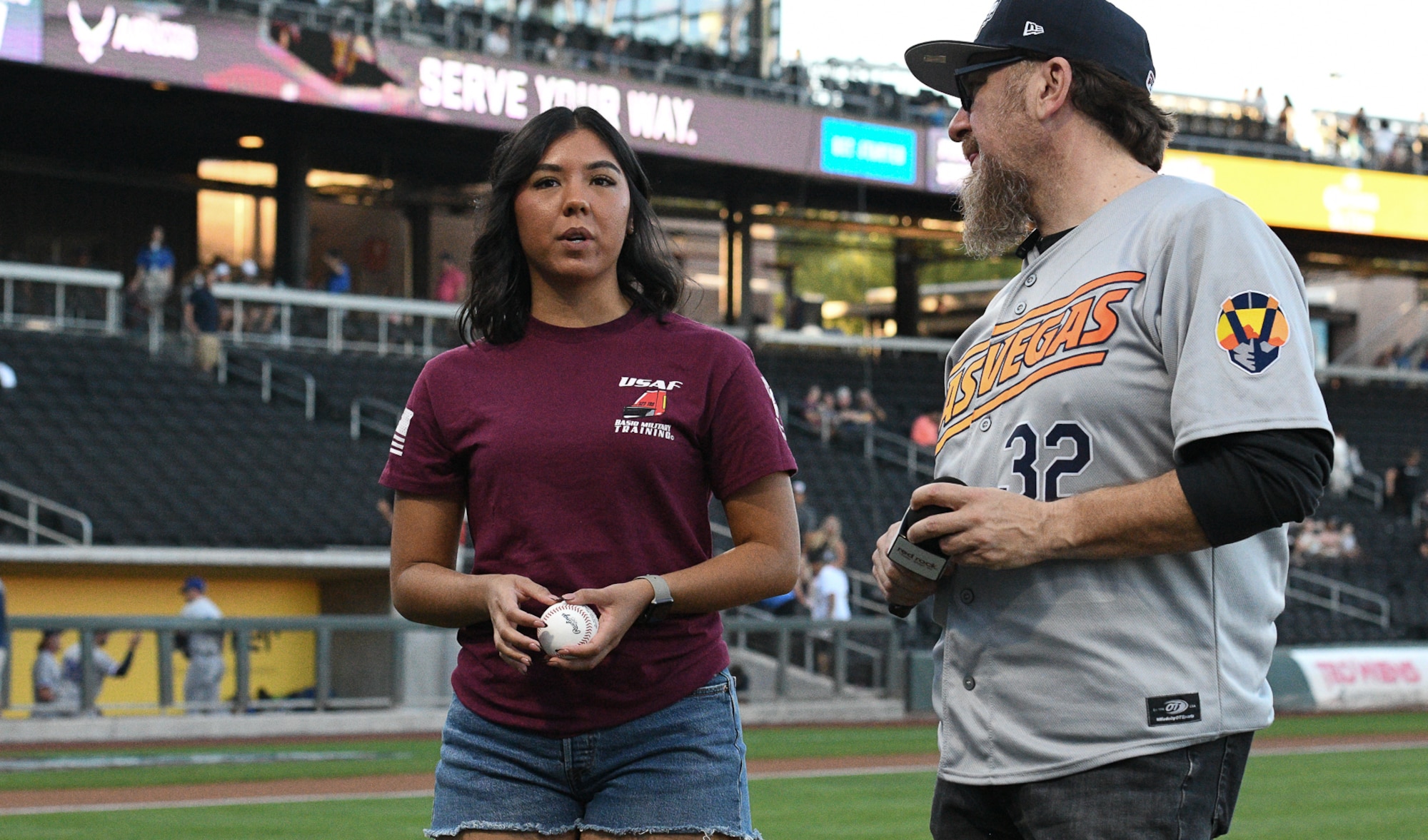 Airman 1st Class Lea Williams, an Airman with the Nevada Air National Guard talks with an infield emcee before throwing the first pitch at a Minor League Baseball, Triple-A National Championship game inside Las Vegas Ballpark at Summerlin, Nevada, Oct. 1, 2022.