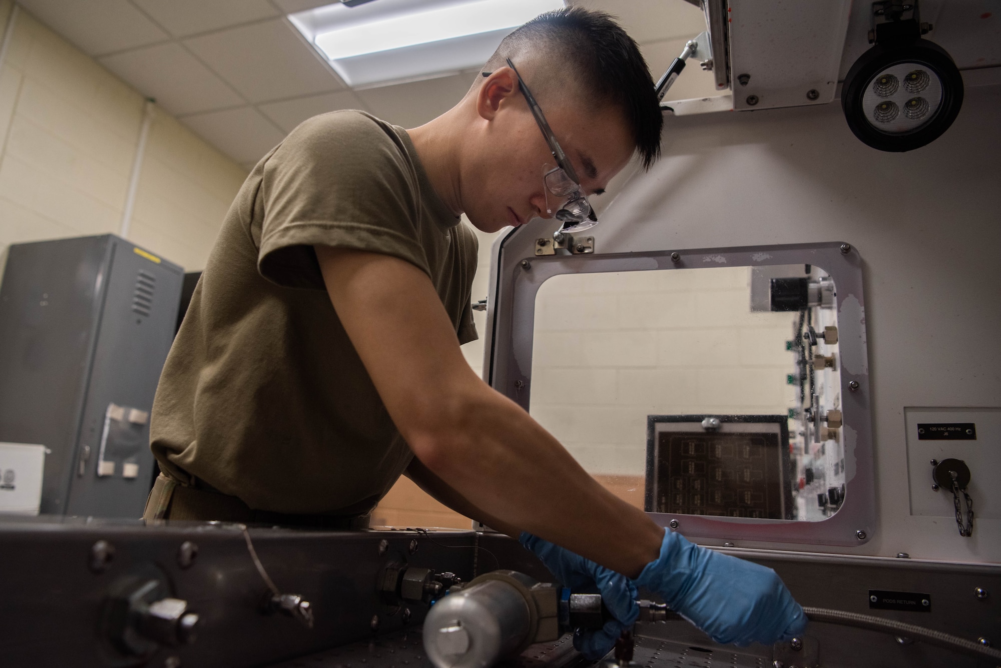 An Airman attaches test tubing to a hydraulic component.