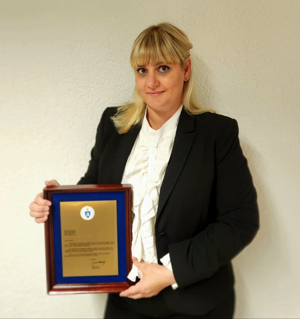 woman in business attire holding award