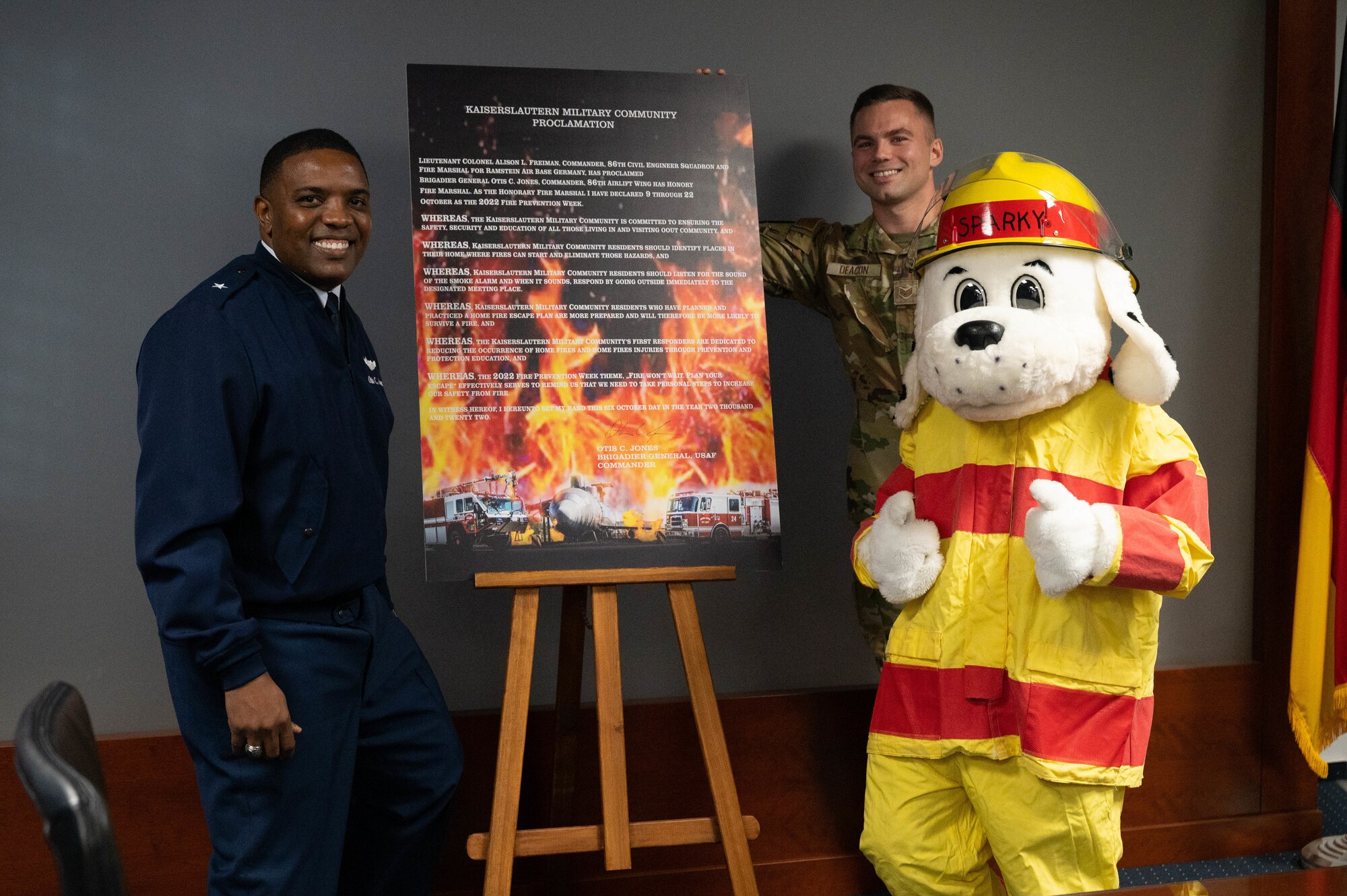 U.S. Air Force Brig. Gen. Otis C. Jones, left, 86th Airlift Wing commander, Staff Sgt. Craig Deacon, center, 86th Civil Engineer Squadron noncommissioned officer in charge of fire prevention, and Sparky the Fire Dog pose for a photo