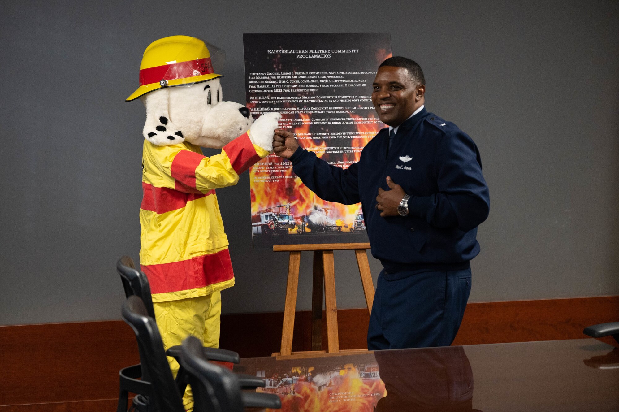 U.S. Air Force Brig. Gen. Otis C. Jones, 86th Airlift Wing commander, fist bumps Sparky the Fire Dog before signing a proclamation