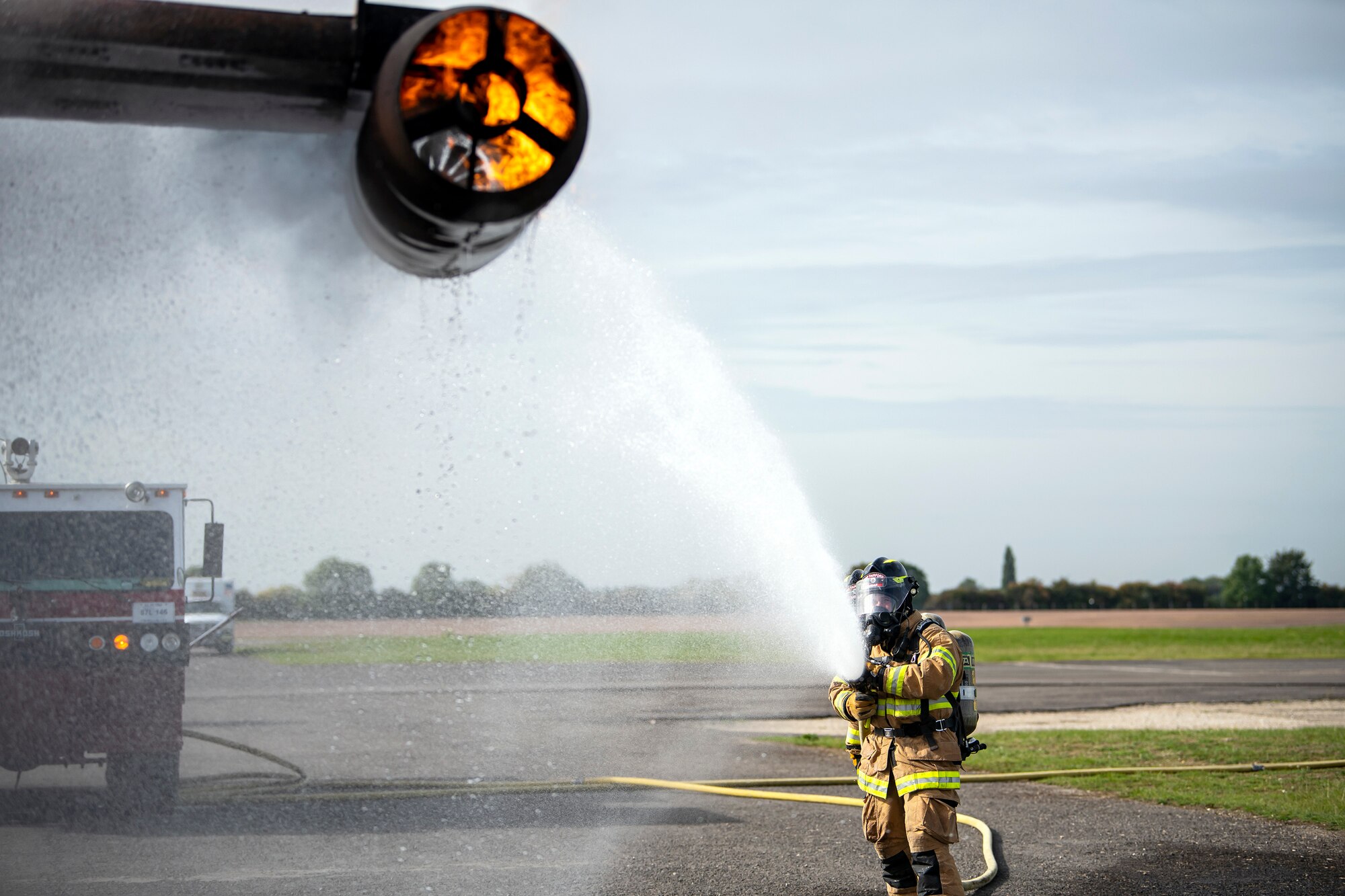 A firefighter from the 422d Fire Emergency Services extinguishes an aircraft fire during a live-fire training exercise at RAF Fairford, England, Oct. 3, 2022. Firefighters from the 422d FES are required to complete live-fire training bi-annually to test their overall readiness and ability to properly extinguish an aircraft fire. (U.S. Air Force photo by Staff Sgt. Eugene Oliver)