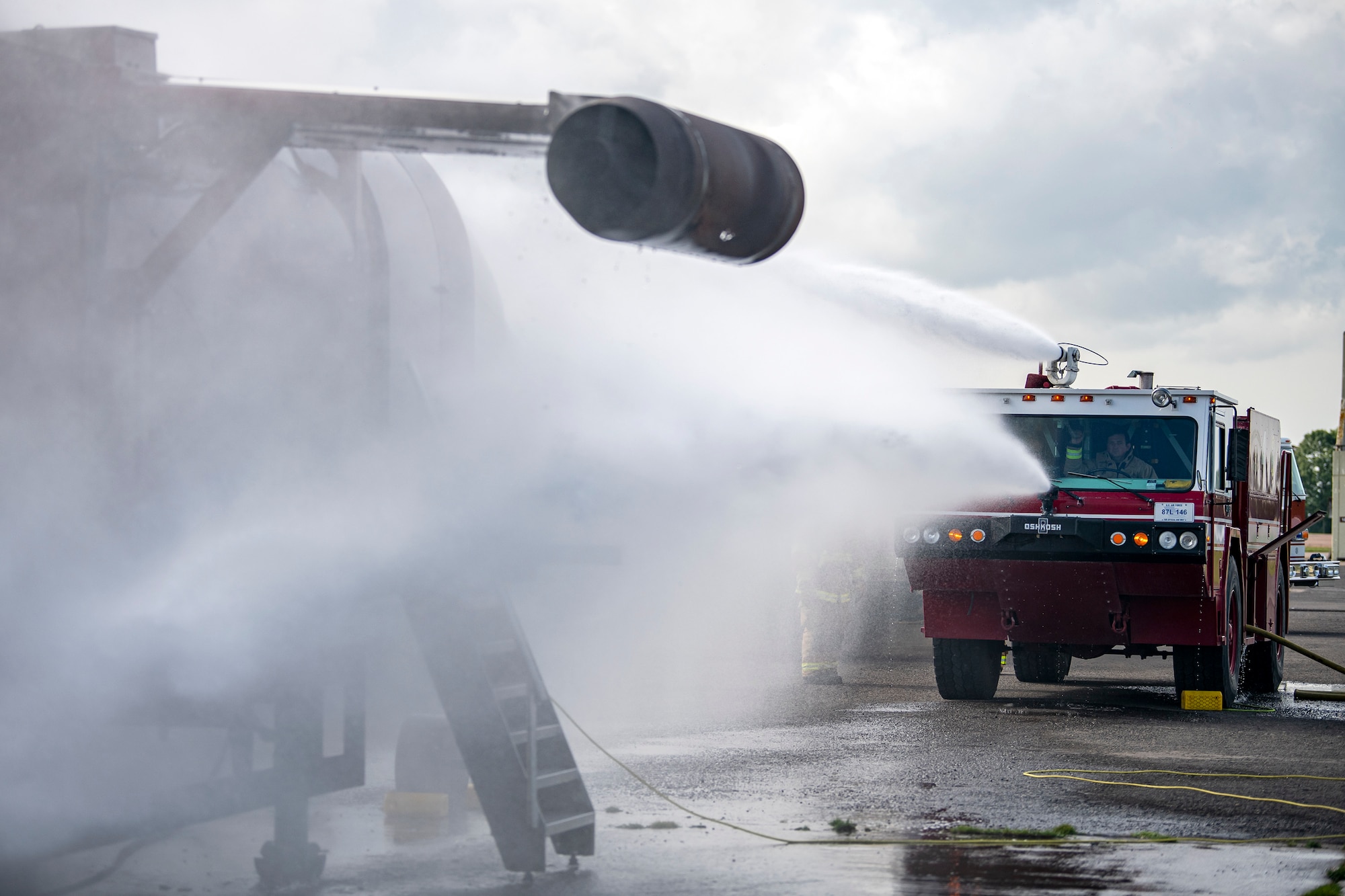 A firetruck from the 422d Fire Emergency Services extinguishes an aircraft fire during  a live-fire training exercise at RAF Fairford, England, Oct. 3, 2022. Firefighters from the 422d FES, are required to complete live-fire training bi-annualy to test thief overall readiness and ability to properly extinguish an aircraft fire. (U.S. Air Force photo by Staff Sgt. Eugene Oliver)