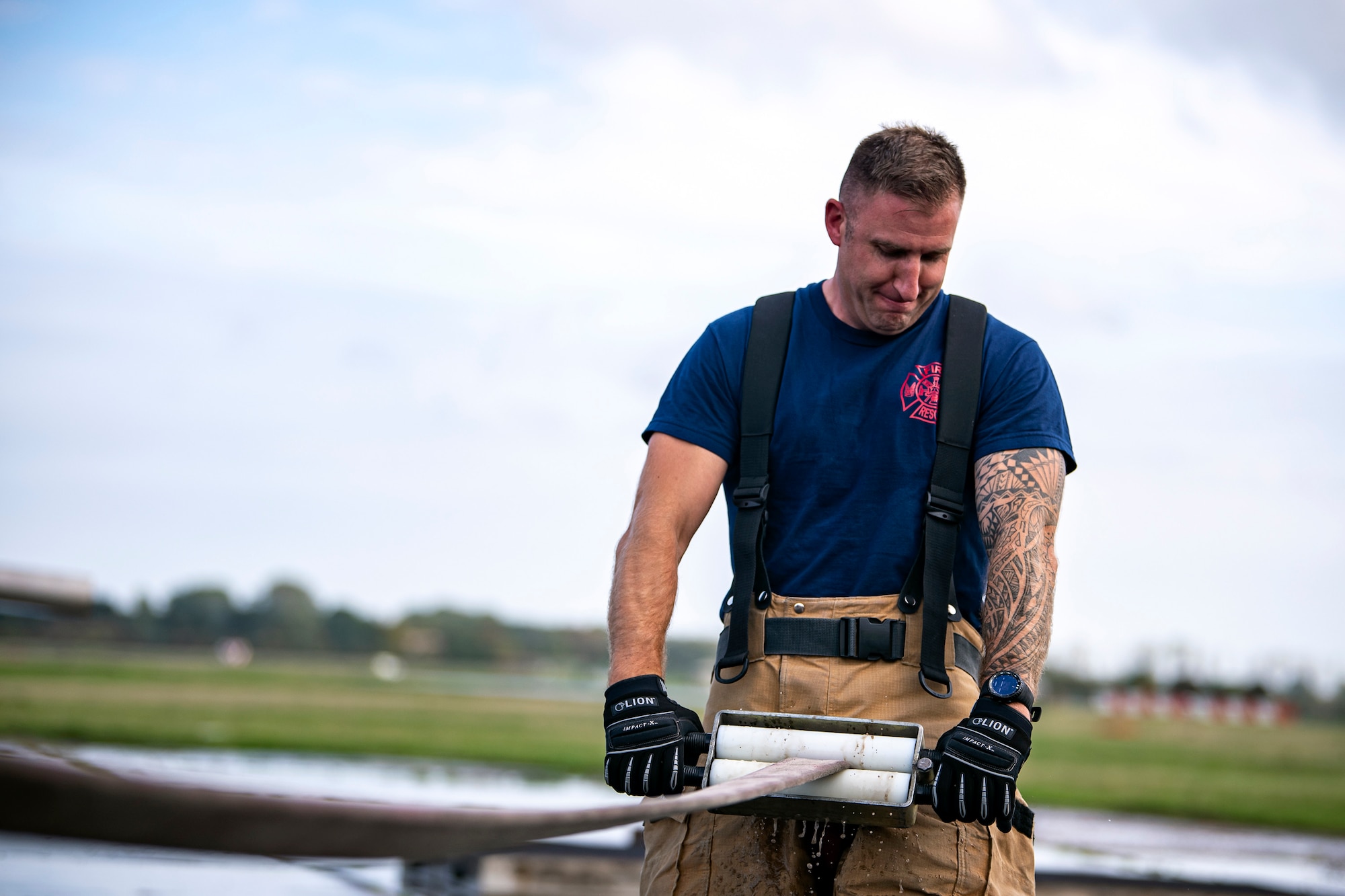 A firefighter from the 422d Fire Emergency Services, empties a fire hose following a live-fire training exercise at RAF Fairford, England, Oct. 3, 2022. Firefighters from the 422d FES, are required to complete live-fire training bi-annualy to test thief overall readiness and ability to properly extinguish an aircraft fire. (U.S. Air Force photo by Staff Sgt. Eugene Oliver)