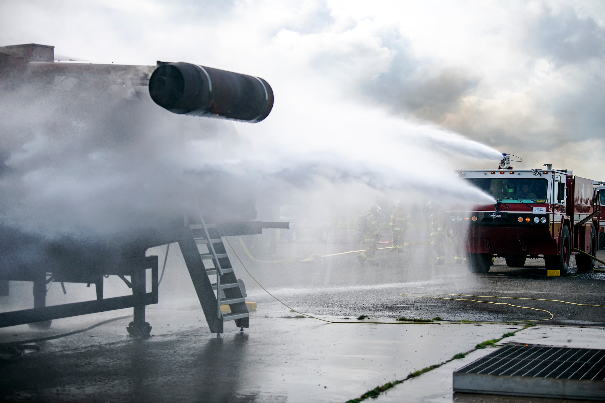 A firetruck from the 422d Fire Emergency Services extinguishes an aircraft fire during  a live-fire training exercise at RAF Fairford, England, Oct. 3, 2022. Firefighters from the 422d FES, are required to complete live-fire training bi-annualy to test thief overall readiness and ability to properly extinguish an aircraft fire. (U.S. Air Force photo by Staff Sgt. Eugene Oliver)