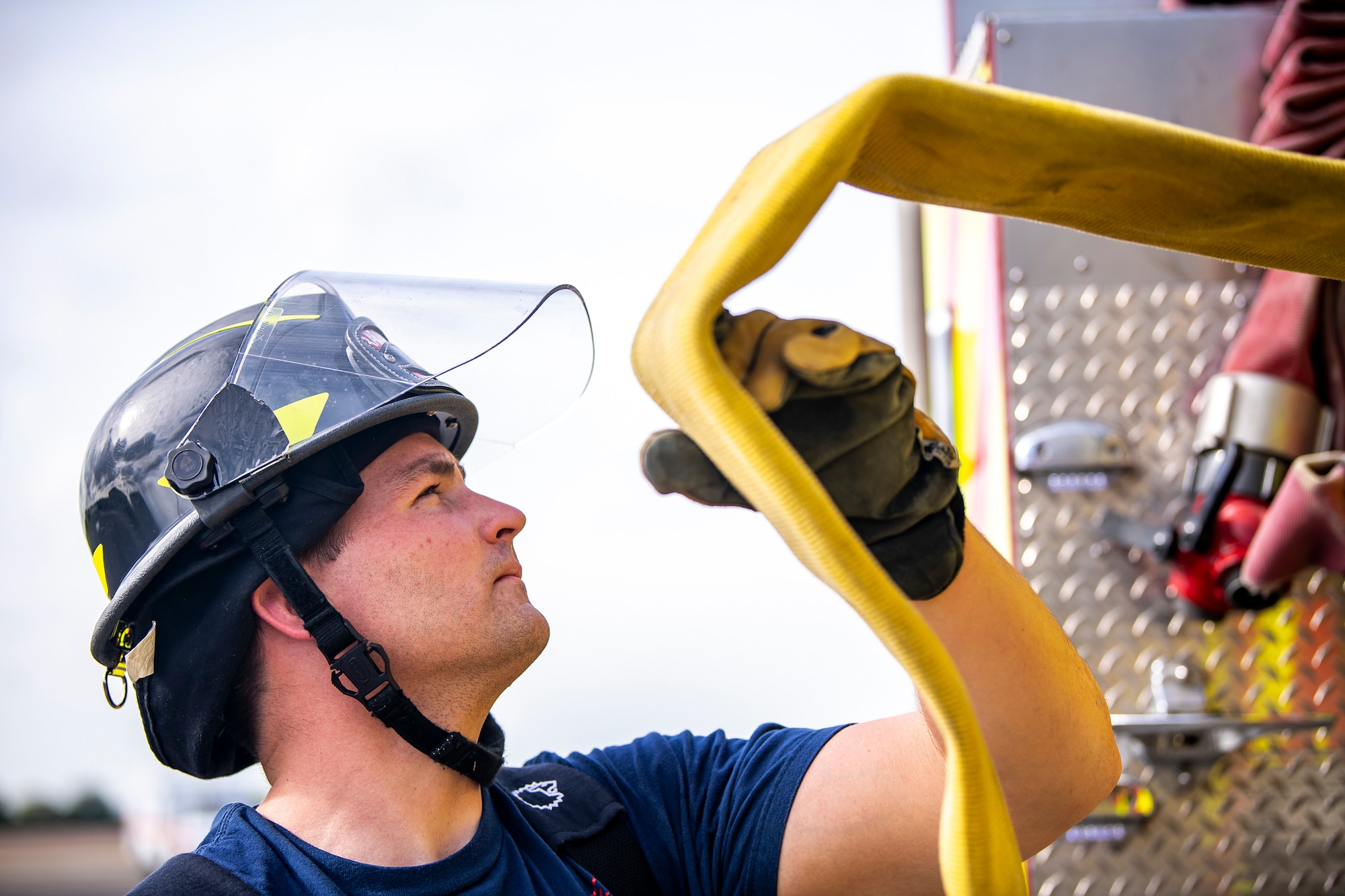 A firefighter from the 422d Fire Emergency Services rolls a fire hose following a live-fire training exercise at RAF Fairford, England, Oct. 3, 2022. Firefighters from the 422d FES, are required to complete live-fire training bi-annually to test thief overall readiness and ability to properly extinguish an aircraft fire. (U.S. Air Force photo by Staff Sgt. Eugene Oliver)