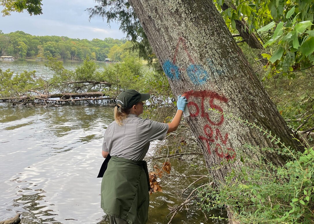 Park Ranger Tiffannie “Chee” Hill covers unsightly graffiti on a tree at Stark Knob Boat Ramp on Old Hickory Lake in Hendersonville, Tennessee. Volunteers and park rangers covered graffiti located on several trees and park benches during National Public Lands Day.