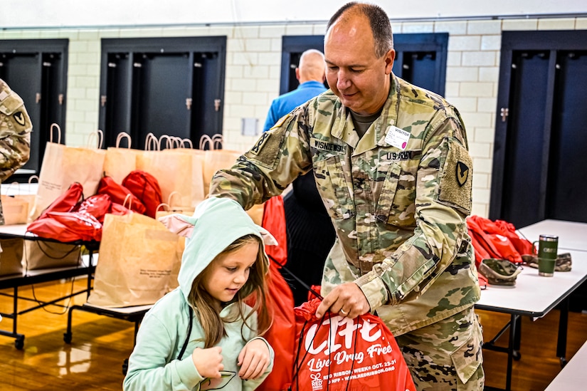 U.S. Army Command Sgt. Maj. James Van Zlike and U.S. Army Col. Mitchell Wisniewski, Army Support Activity Fort Dix command team, hand out bags to elementary school children in support of Red Ribbon Week awareness on Oct. 6, 2022, at Joint Base McGuire-Dix-Lakehurst, N.J. Red Ribbon Week is observed and celebrated the last week of October, it is the largest and longest running drug awareness program nationwide.