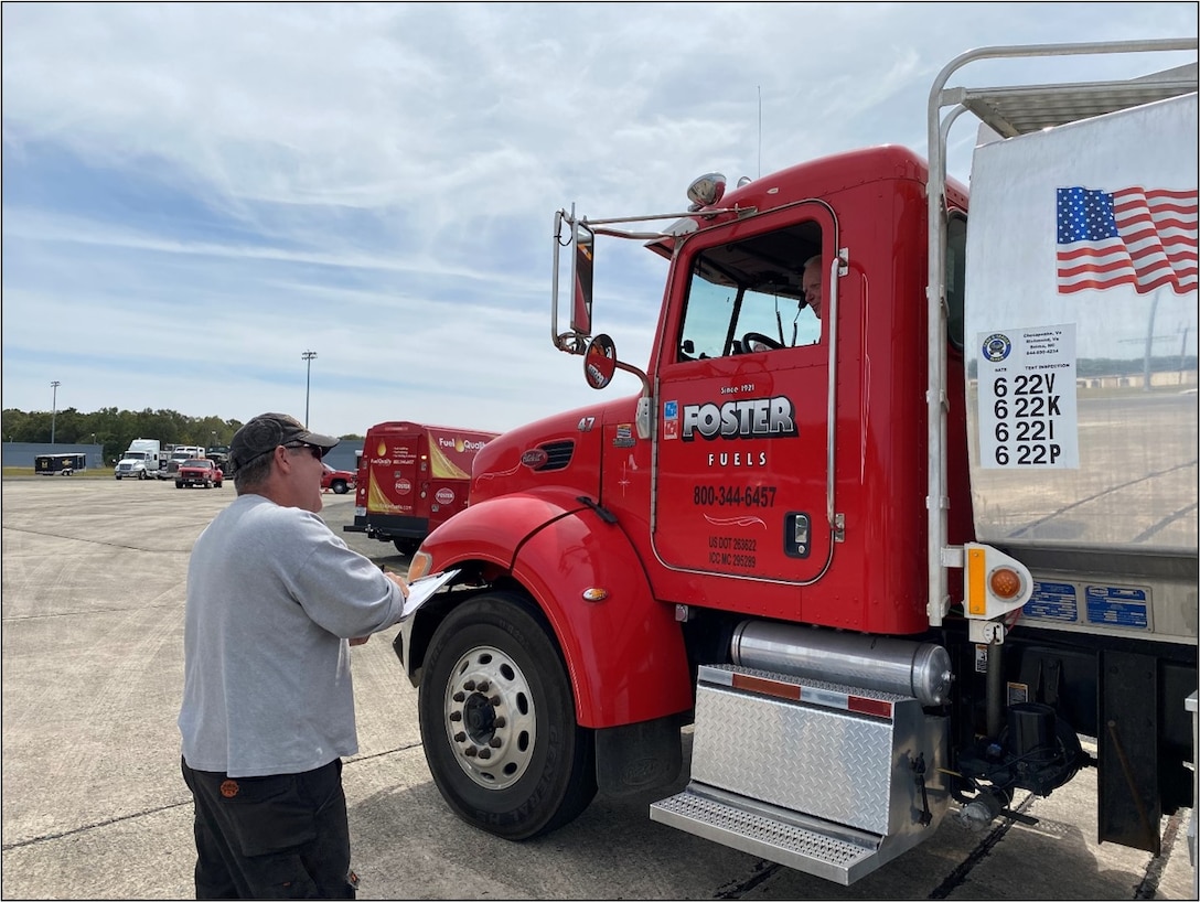 a man stands beside a fuel tank truck
