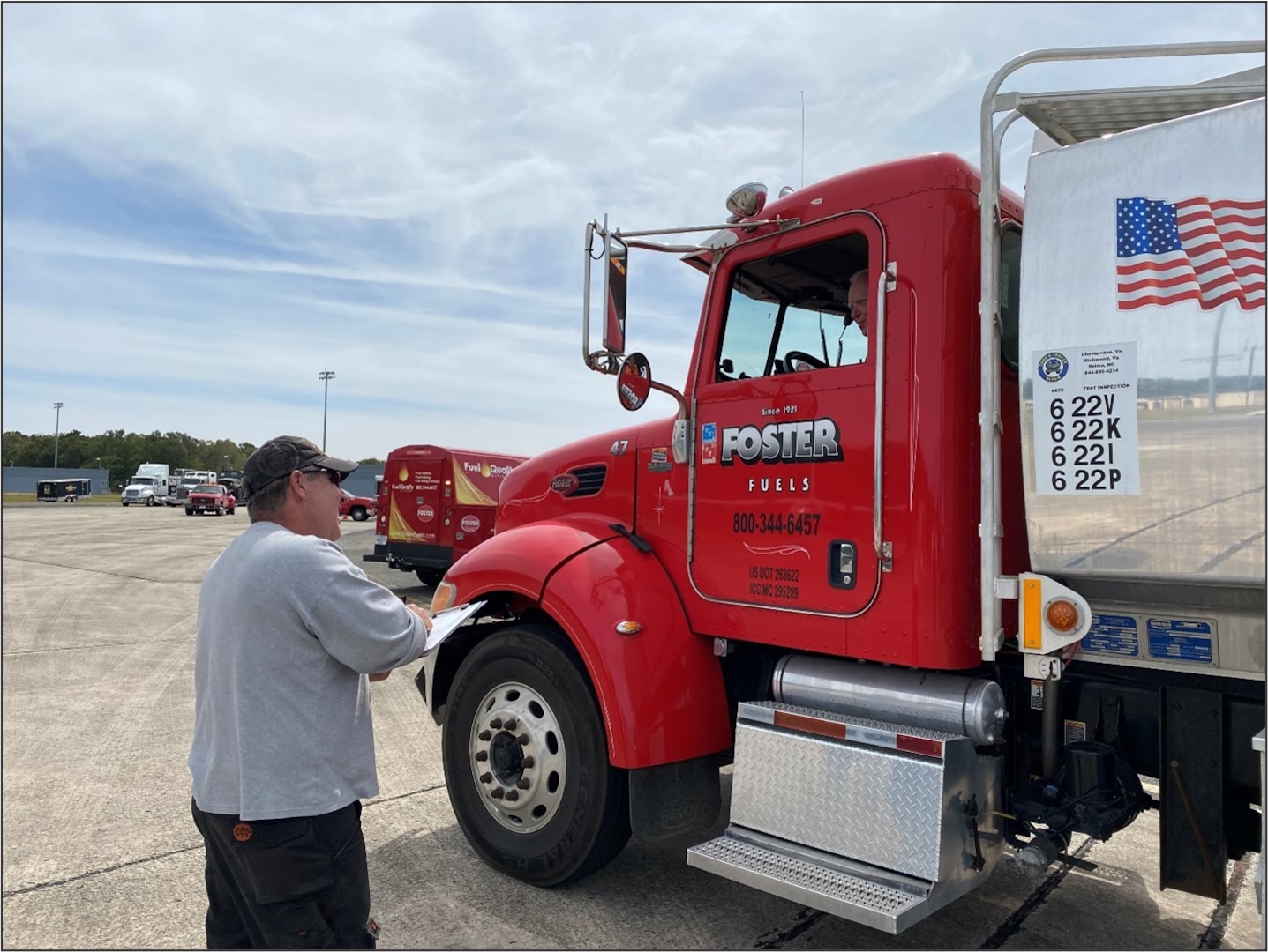 a man stands beside a fuel tank truck