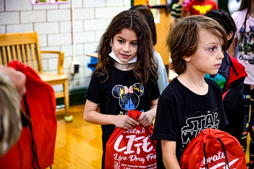 U.S. Army Command Sgt. Maj. James Van Zlike and U.S. Army Col. Mitchell Wisniewski, Army Support Activity Fort Dix command team, hand out bags to elementary school children in support of Red Ribbon Week awareness on Oct. 6, 2022, at Joint Base McGuire-Dix-Lakehurst, N.J. Red Ribbon Week is observed and celebrated the last week of October, it is the largest and longest running drug awareness program nationwide.