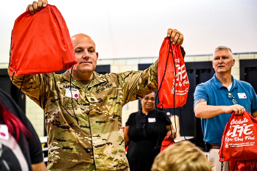 U.S. Army Command Sgt. Maj. James Van Zlike and U.S. Army Col. Mitchell Wisniewski, Army Support Activity Fort Dix command team, hand out bags to elementary school children in support of Red Ribbon Week awareness on Oct. 6, 2022, at Joint Base McGuire-Dix-Lakehurst, N.J. Red Ribbon Week is observed and celebrated the last week of October, it is the largest and longest running drug awareness program nationwide.