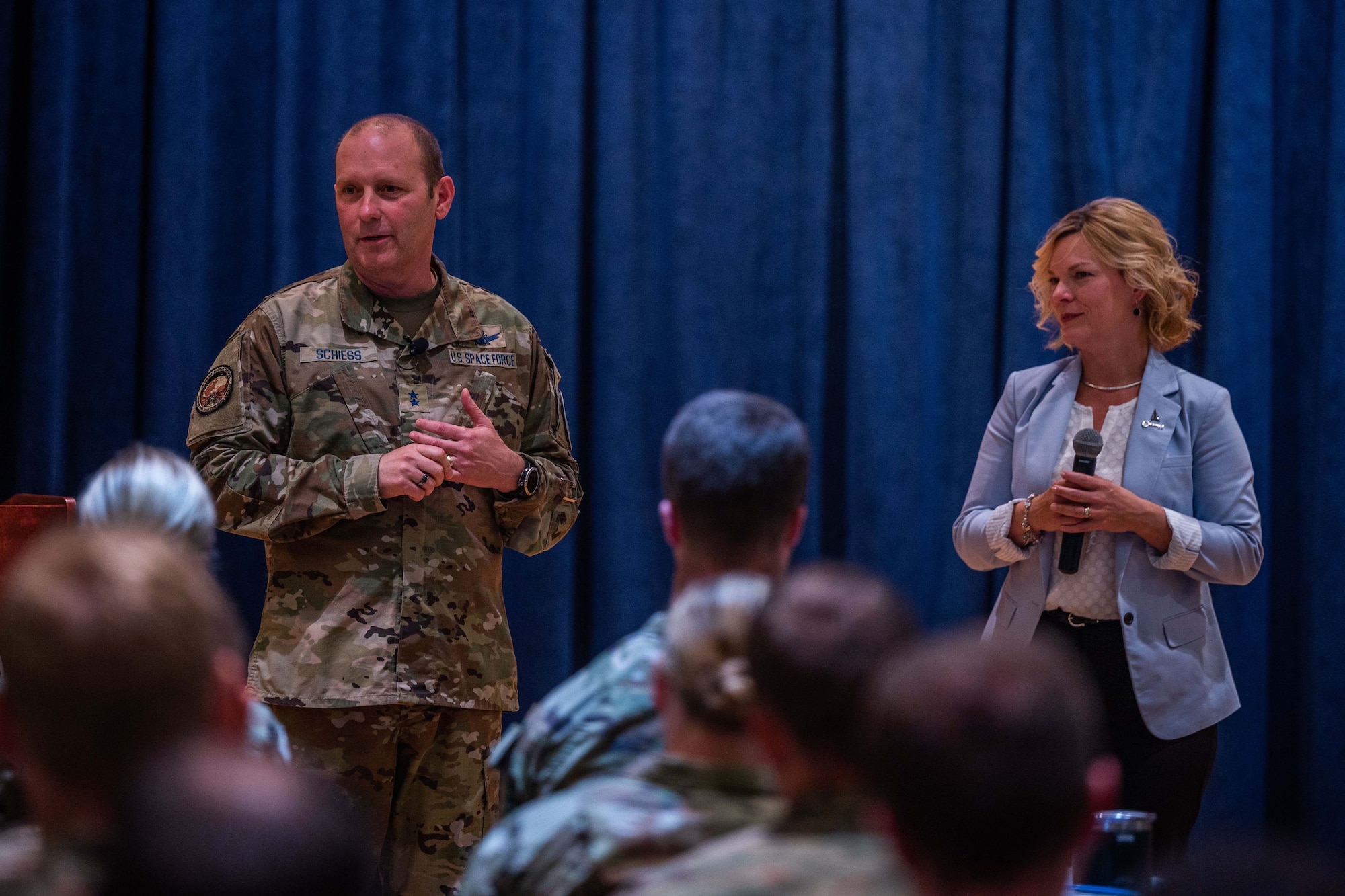 U.S. Space Force Maj. Gen. Douglas A. Schiess, Combined Force Space Component Command commander, left, and Mrs. Debbie Schiess, address audience members during the General’s first All Call as CFSCC commander at Vandenberg Space Force Base, Calif., Aug. 30, 2022. The couple has been together for over 30 years, and this will there third time at Vandenberg. (U.S. Space Force photo by Tech. Sgt. Luke Kitterman)