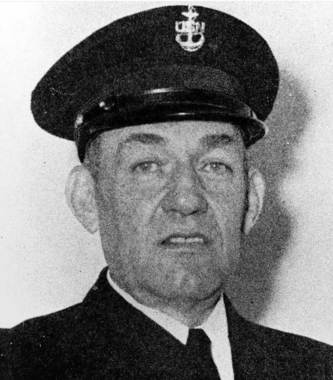 A man in dress uniform and cap poses for a photo.