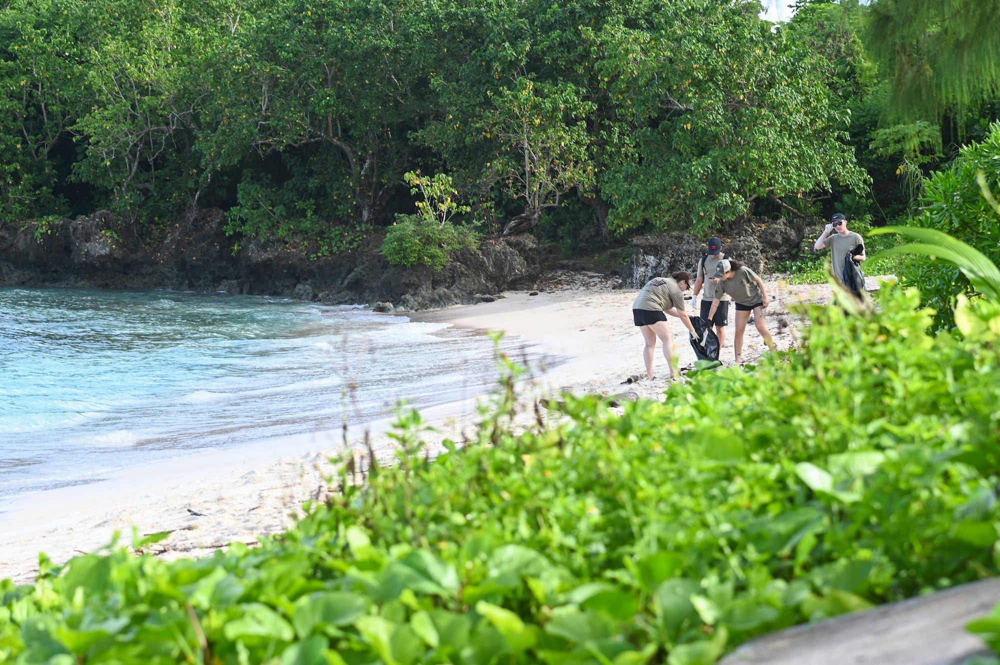 Airmen pick up trash from a beach.