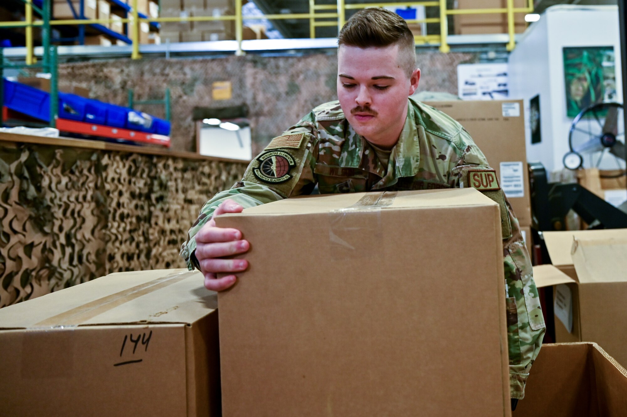 Staff Sgt. Jacob Wilson, 90th Logistics Readiness Squadron mobility NCOIC, moves boxes of parkas into a shipping container on F.E. Warren Air Force Base, Wyoming, Sept. 29, 2022. As part of a Department of Defense effort to provide foreign aid, the 90 LRS mobility flight packed and shipped 111 parkas to the front lines in Eastern Europe. (U.S. Air Force photo by Joseph Coslett)