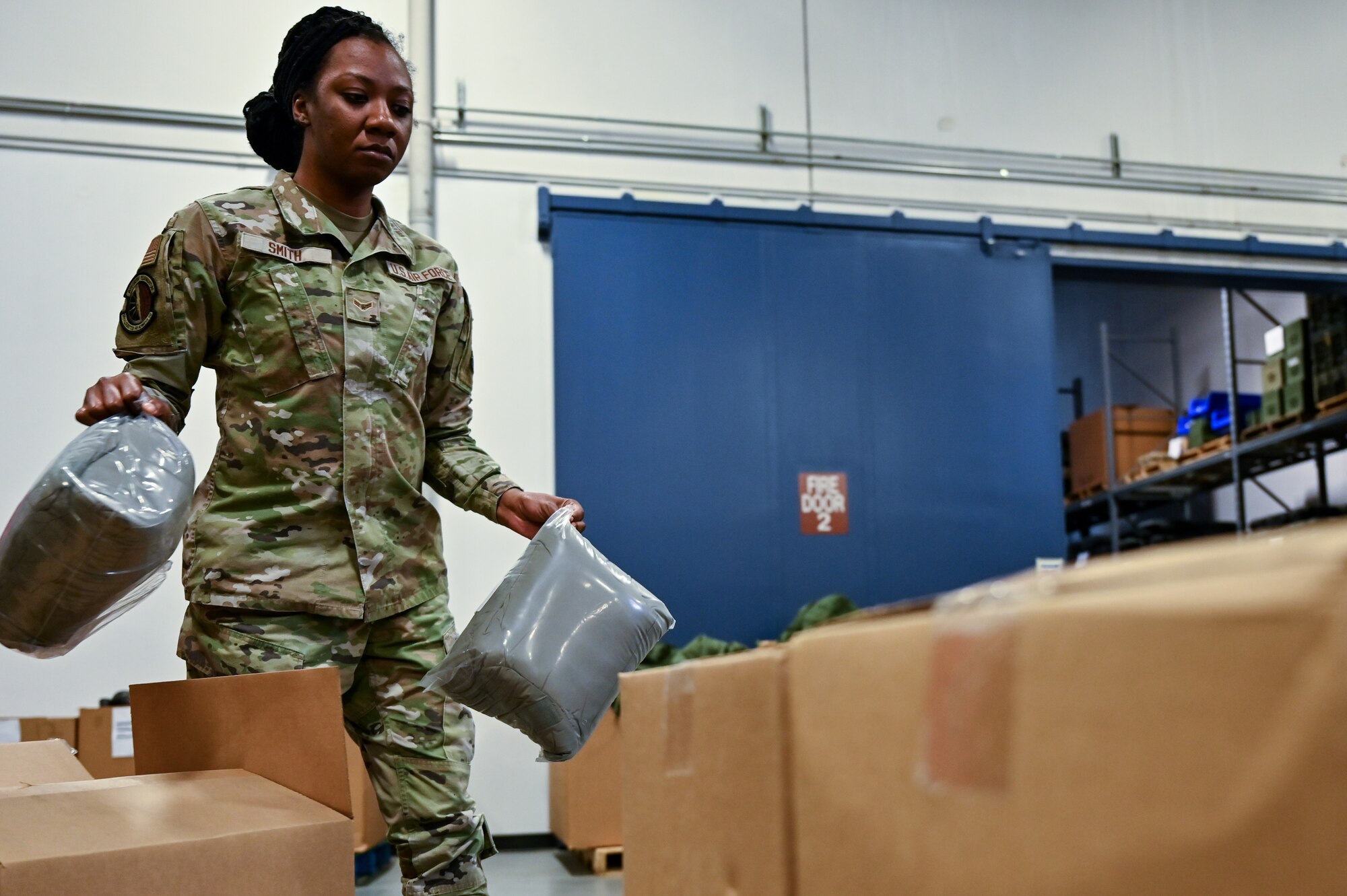 Airman 1st Class Destiny Smith, 90th Logistics Readiness Squadron mobility journeyman, transfers parkas into a shipping container on F.E. Warren Air Force Base, Wyoming, Sept. 29, 2022. As part of a Department of Defense effort to provide foreign aid, the 90 LRS mobility flight packed and shipped 111 parkas to the front lines in Eastern Europe. (U.S. Air Force photo by Joseph Coslett)