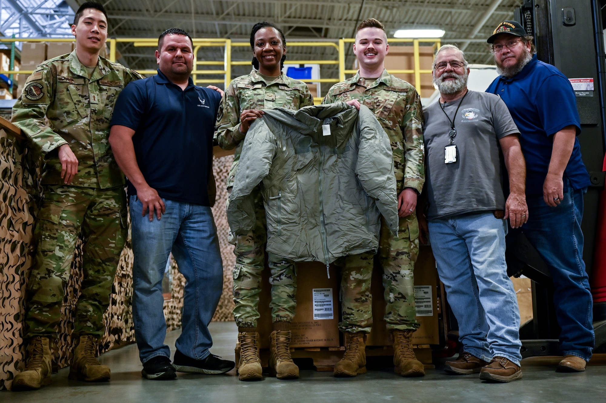 The 90th Logistics Readiness Squadron mobility team hold a parka to show what they packed on F.E. Warren Air Force Base, Wyoming, Sept. 29, 2022. As part of a Department of Defense effort to provide foreign aid, the 90 LRS mobility flight packed and shipped 111 parkas to the front lines in Eastern Europe. (U.S. Air Force photo by Joseph Coslett)