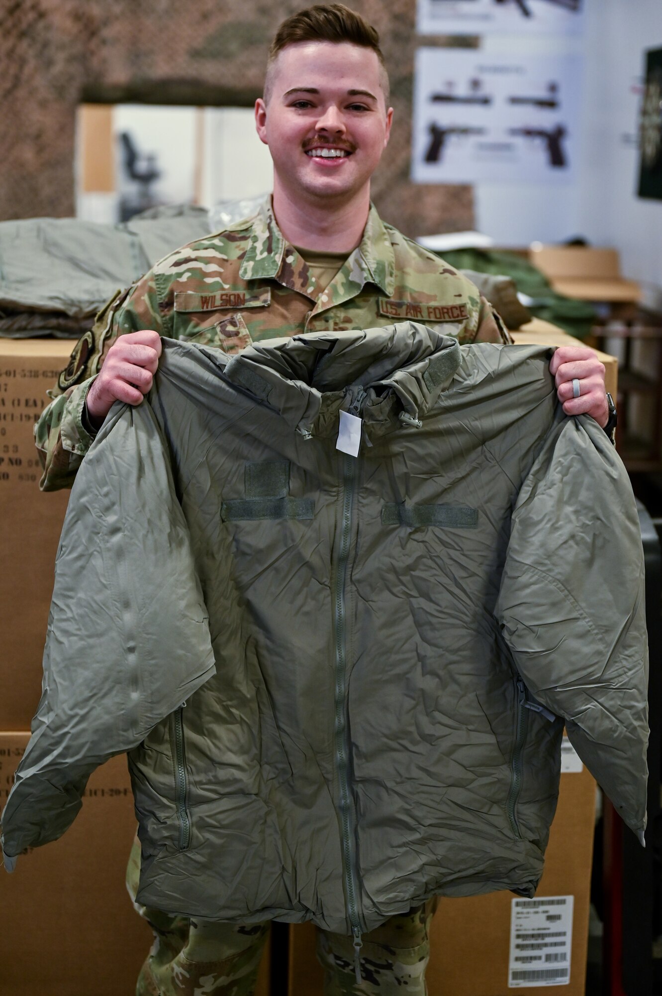 Staff Sgt. Jacob Wilson, 90th Logistics Readiness Squadron mobility NCOIC, holds a parka to demonstrate what the 90 LRS packed on F.E. Warren Air Force Base, Wyoming, Sept. 29, 2022. As part of a Department of Defense effort to provide foreign aid, the 90 LRS mobility flight packed and shipped 111 parkas to the front lines in Eastern Europe. (U.S. Air Force photo by Joseph Coslett)