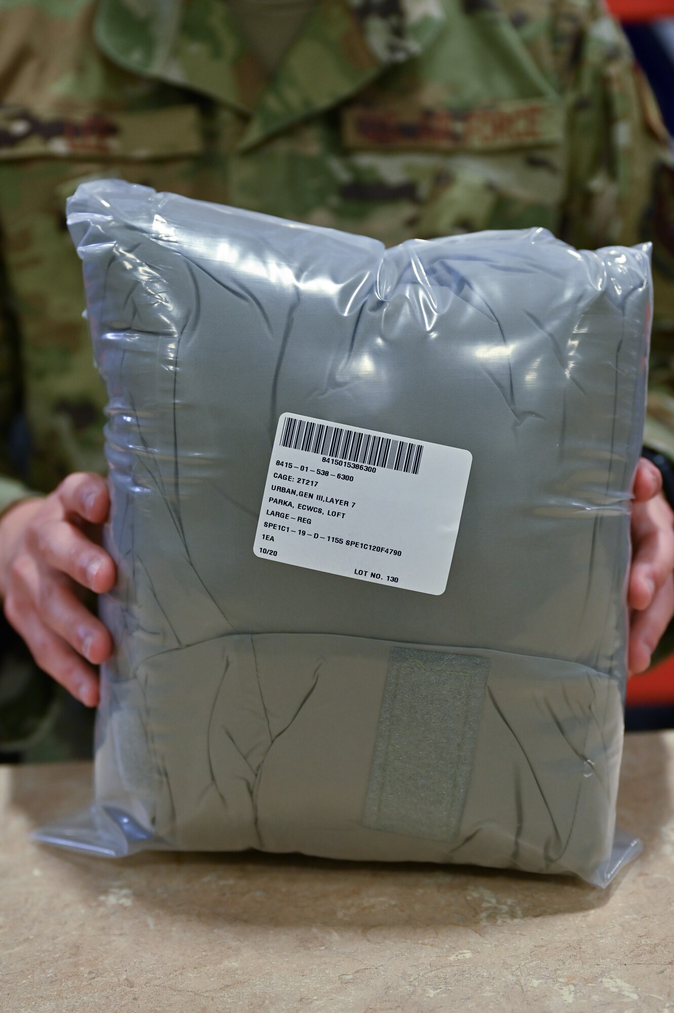 2nd Lt. Kevin Lee, 90th Logistics Readiness Squadron supply flight commander, holds a packed parka on F.E. Warren Air Force Base, Wyoming, Sept. 29, 2022. As part of a Department of Defense effort to provide foreign aid, the 90 LRS mobility flight packed and shipped 111 parkas to the front lines in Eastern Europe. (U.S. Air Force photo by Joseph Coslett)
