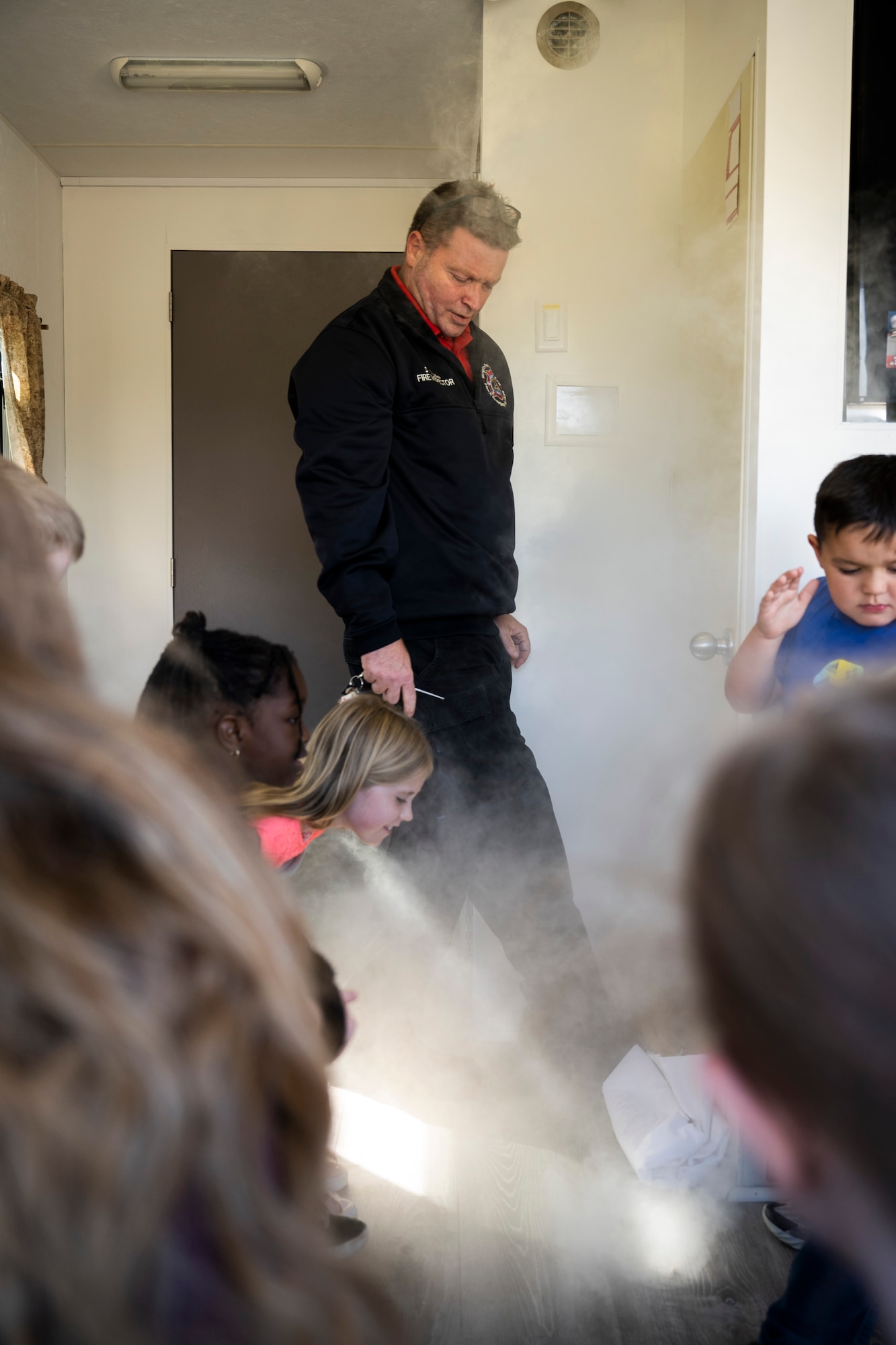 A fireman simulates smoke to children.
