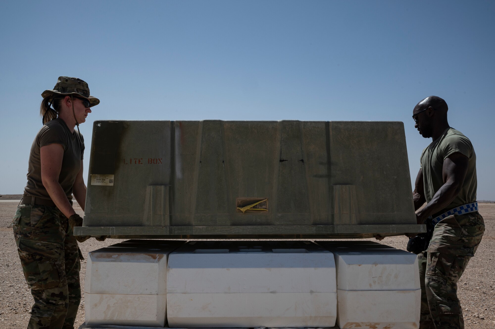 U.S. Air Force Weather Flight Commander Capt Britta Gjermo, left, 332d Expeditionary Operations Support Squadron, assists an Airman with off-loading munitions during a training exercise designed around Agile Combat Employment, at an undisclosed location in Southwest Asia, September 27-28, 2022. Capt Gjermo performed tasks outside of her Air Force Specialty Code and demonstrated the multi-capable Airmen concept of learning multiple skill traits. (U.S. Photo by Staff Sgt. Christian Sullivan)