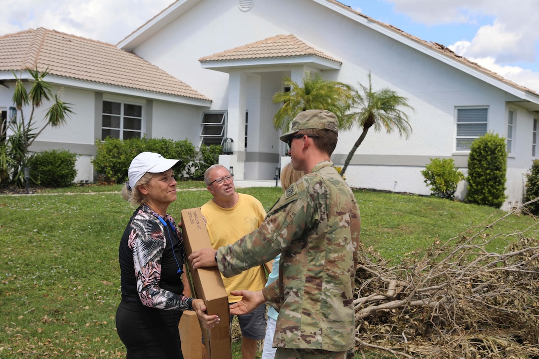 A soldier delivers tarps to residents.