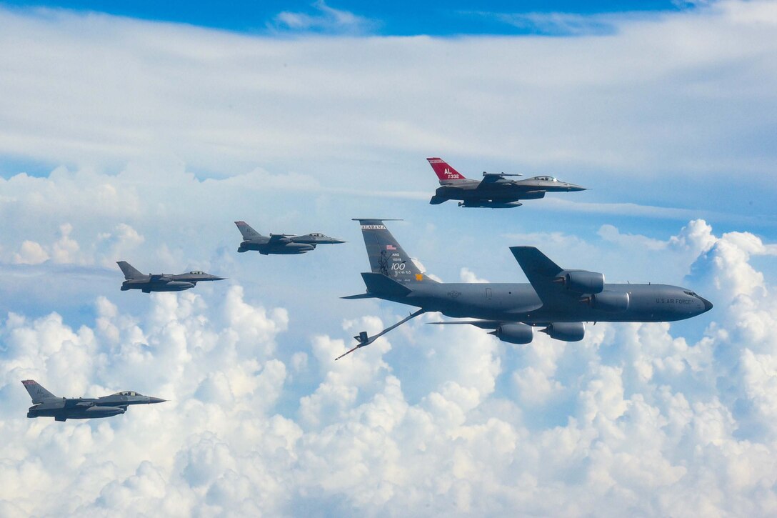 Four smaller aircraft surround a larger aircraft in flight.