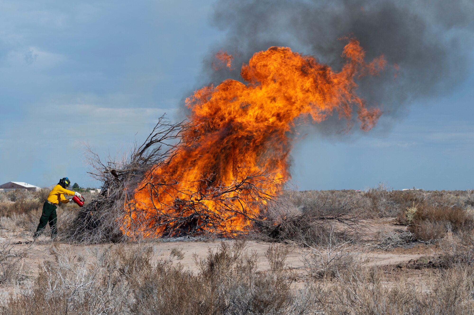 U.S. Air Force Airman 1st Class Joshua Paculan, 49th Civil Engineer Squadron firefighter, ignites a pile of brush during a prescribed burn at Holloman Air Force Base, New Mexico, Oct. 3, 2022. The prescribed burn rid the base of highly flammable dried tree brush in order to cultivate new plant growth. (U.S. Air Force photo by Airman 1st Class Isaiah Pedrazzini)