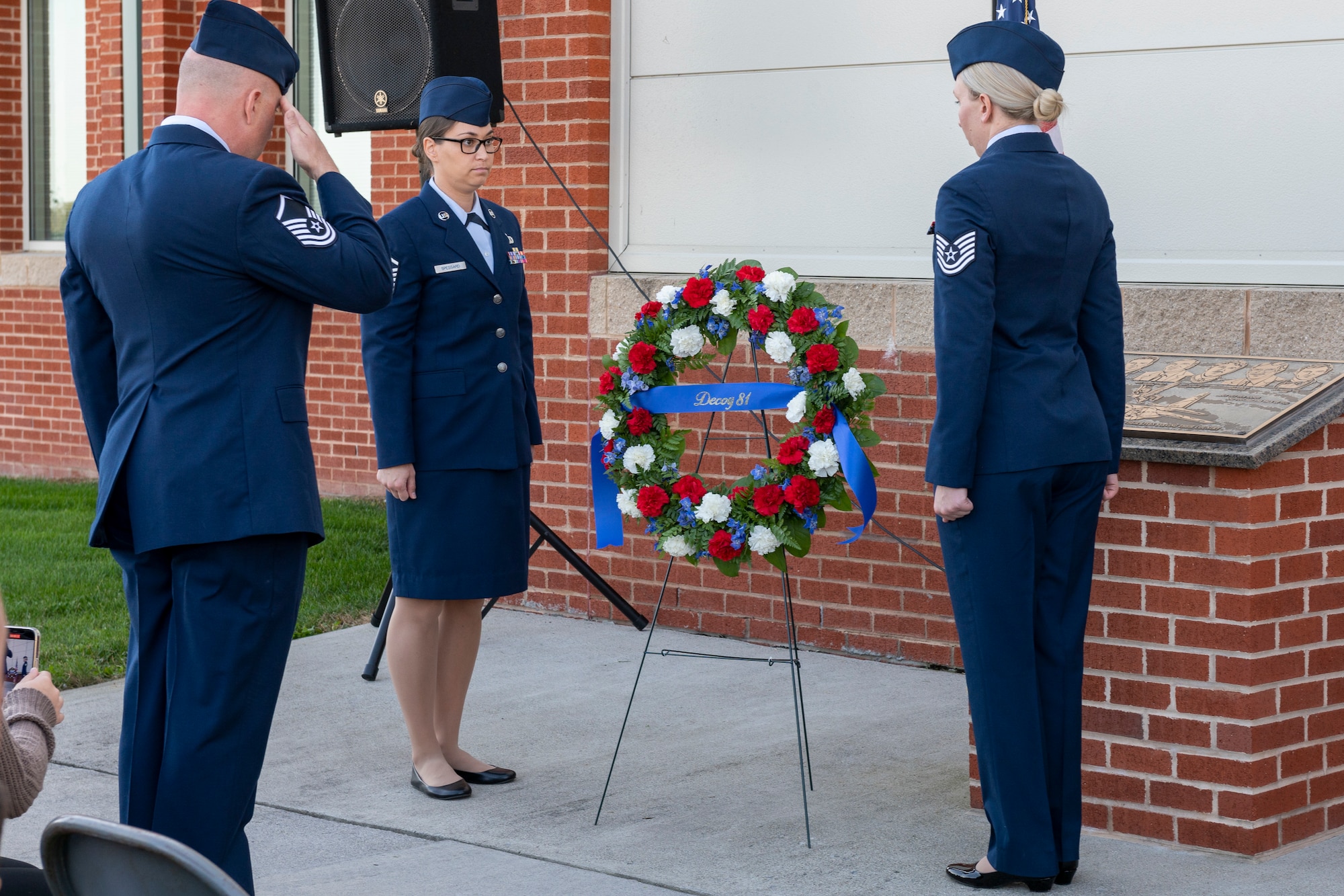 U.S. Air Force Master Sgt. Sterling Hall, Master Sgt. Breanne Spessard and Tech. Sgt. Sarah Hall, all assigned to the 167th Operations Group, place a wreath beside the Decoy 81 memorial plaque in front of the 167th Operations Group building during a memorial ceremony, Oct. 7, 2022, at the 167th Airlift Wing, Martinsburg, West Virginia.