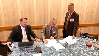 three men at a table signing papers