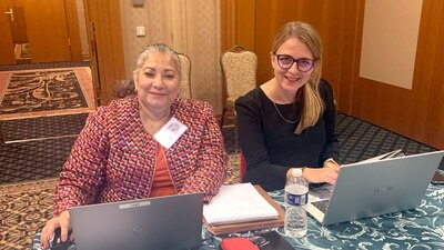 two women sit next to one another with computers