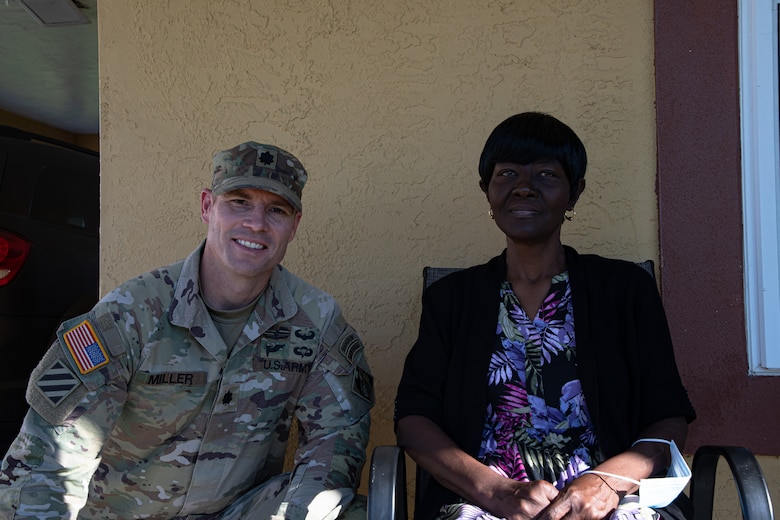 Man in Army uniform sitting next to woman on a porch.