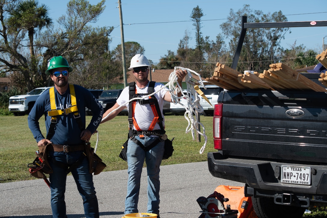 Two workers unload equipment from a pickup truck.