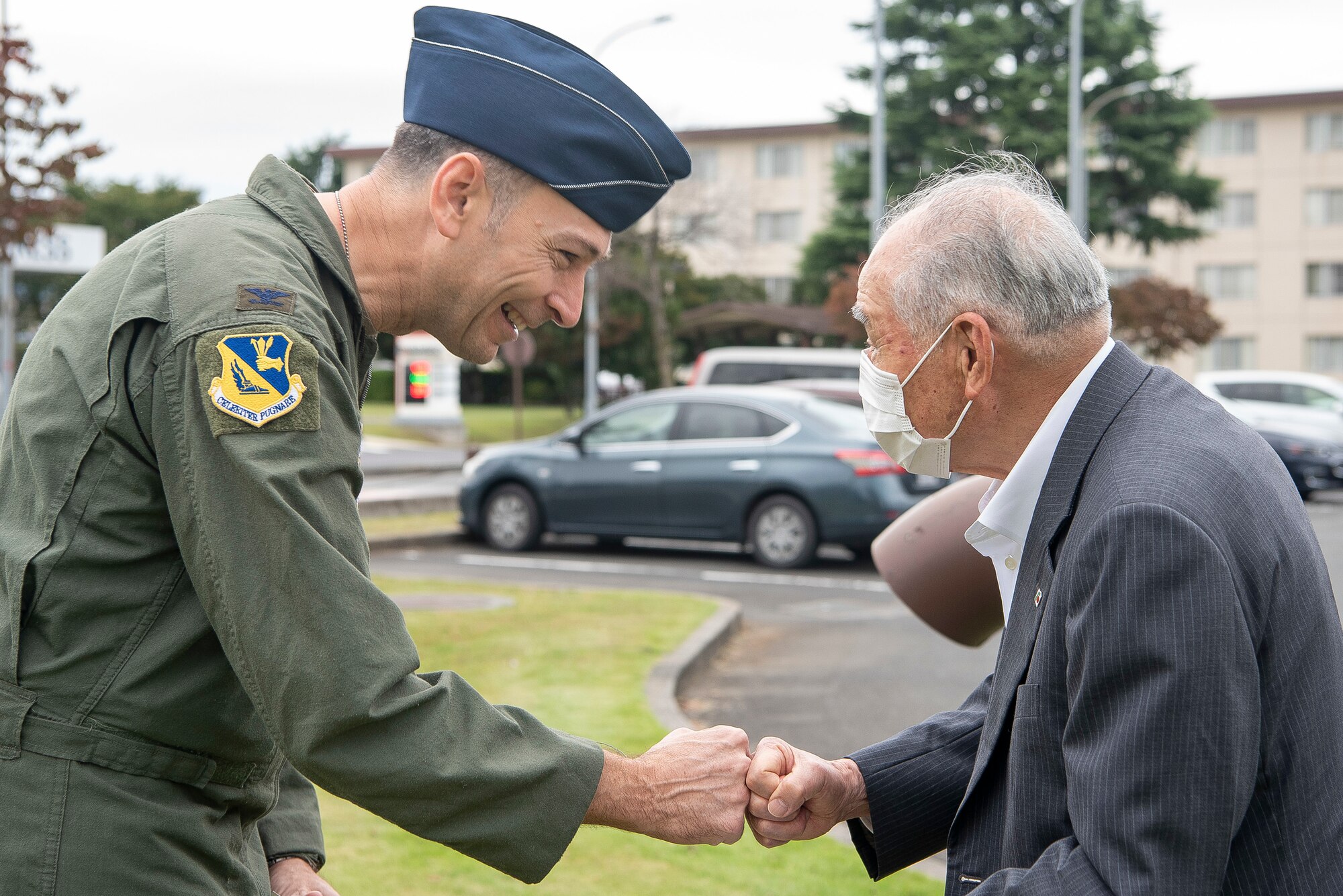 Col. Andrew Roddan, 374th Airlift Wing commander, bumps fists with a member of the Akishima-Yokota Friendship Club during a tree planting ceremony at Yokota Air Base, Japan, Oct. 5, 2022.