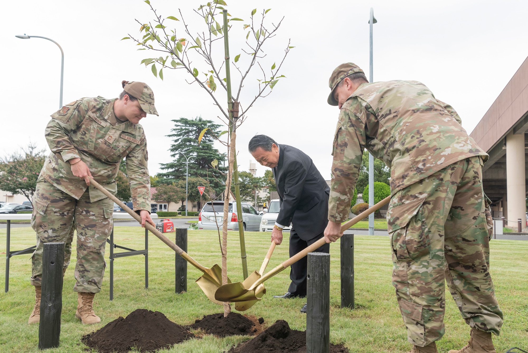 Chief Master Sgt. Jessica Cambron, 374th Mission Support Group senior enlisted leader, left, Fumioki Hirahata, Akishima-Yokota Friendship Club president, center, and Col. Ryan Vetter, 374th Mission Support Group commander, work together to plant a cherry sapling during a ceremony at Yokota Air Base, Japan, Oct. 5, 2022.