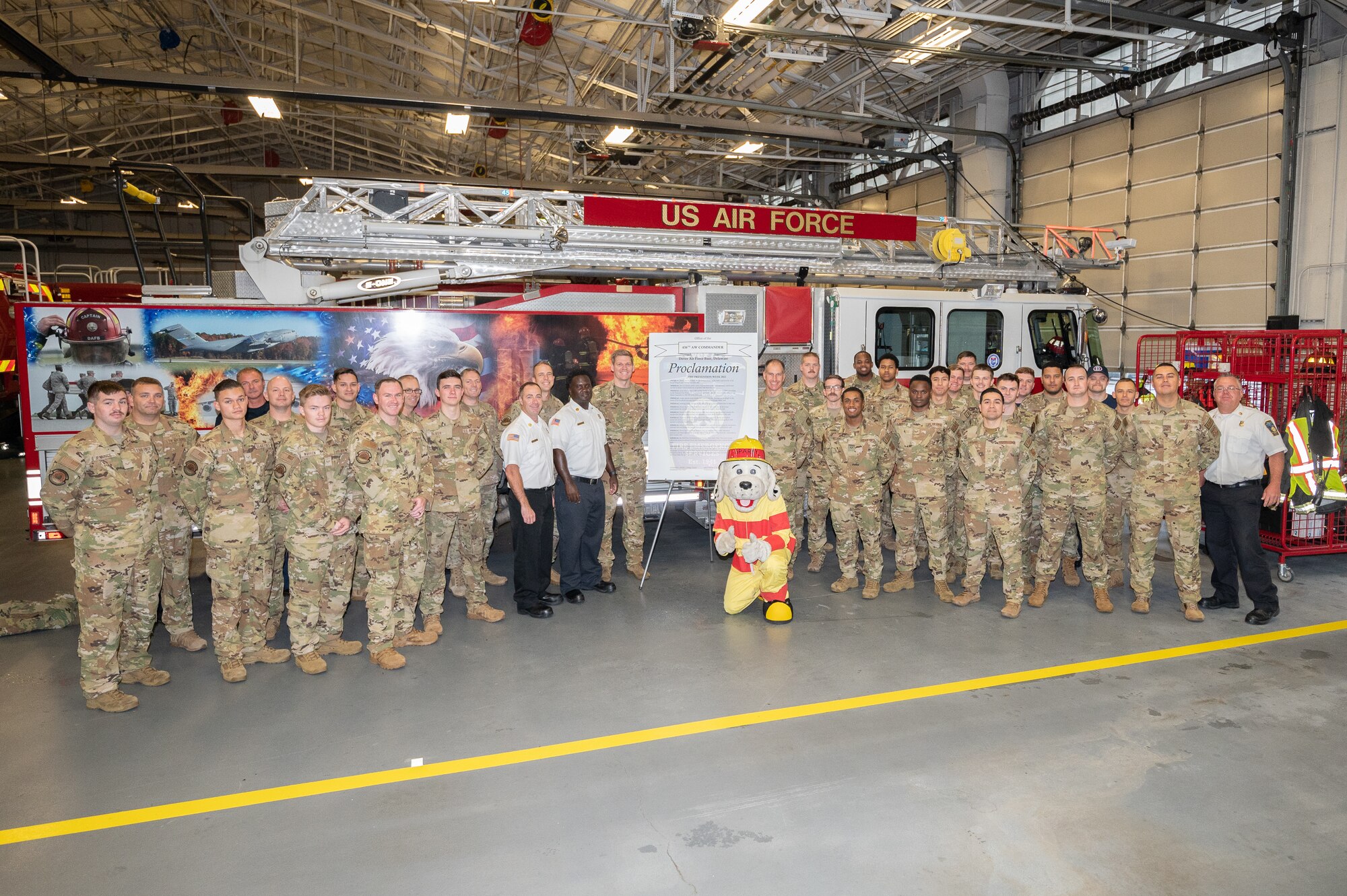 Col. Matt Husmann, 436th Airlift Wing commander, and Chief Master Sgt. Timothy Bayes, 436th AW command chief, stand with Team Dover firefighters and the signed 2022 Fire Prevention Week proclamation, Oct. 4, 2022, at Dover Air Force Base, Delaware. During Fire Prevention Week, the 436th CES firefighters provide the Dover community with lifesaving education in an effort to decrease fire safety hazards. (U.S. Air Force photo by Mauricio Campino)