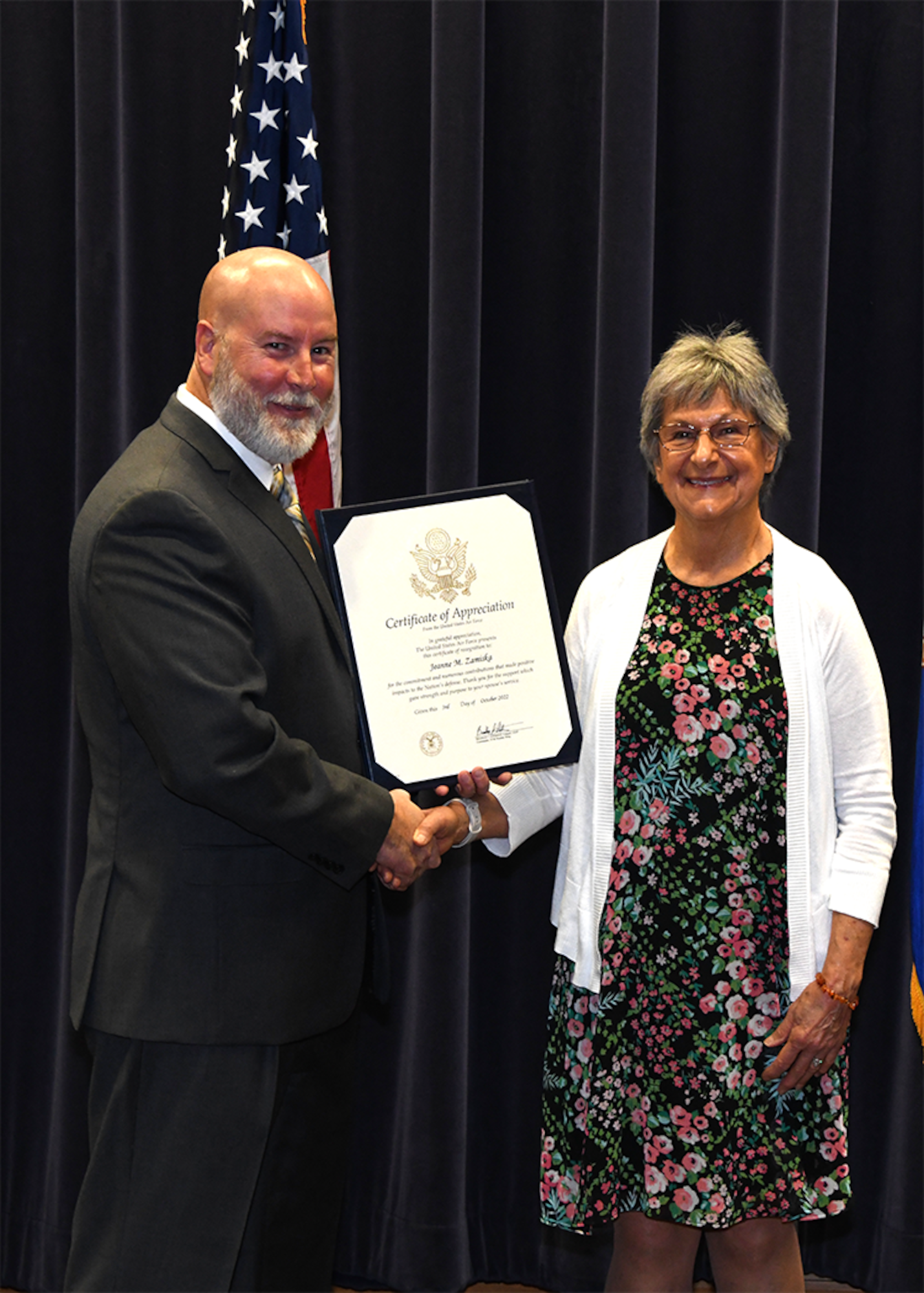 Marty Fagan presents Jeanne Zamiska with a certificate of appreciation during a 50-year retirement ceremony for her husband Paul Alan Zamiska in the 557th Weather Wing’s Chief Master Sgt. Peter Morris auditorium on Offutt Air Force Base, Nebraska Sept. 30.