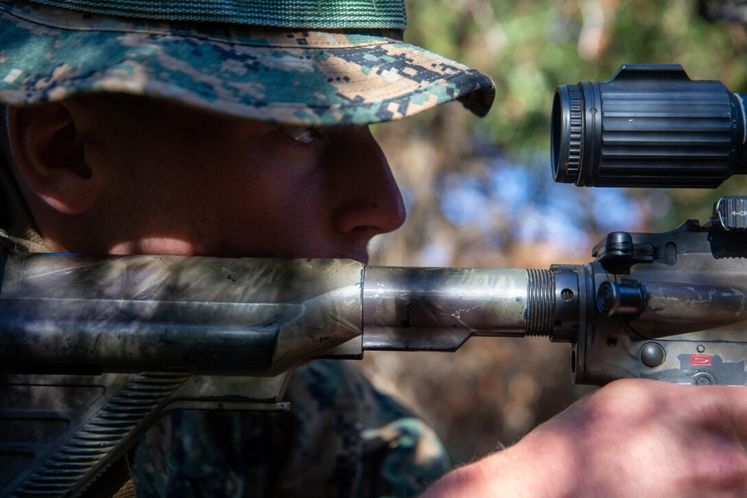 A Marine in camouflage aims a weapon.