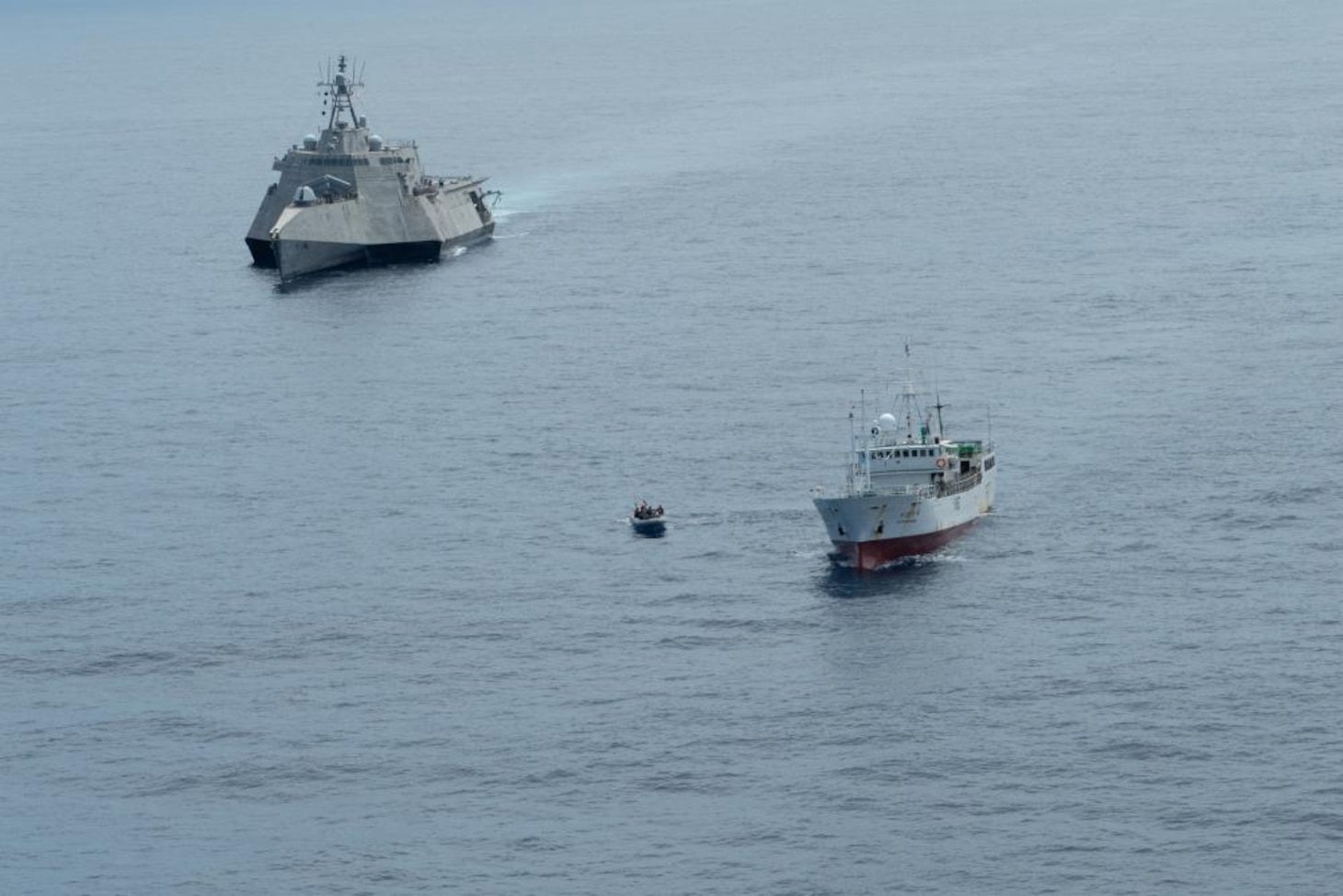 Independence-variant littoral combat ship USS Oakland (LCS 24) stations behind a fishing vessel while Tactical Law Enforcement Team Pacific Coast Guardsmen conduct an Oceania Maritime Support Initiative (OMSI) vessel compliance boarding, Aug. 19, 2022.