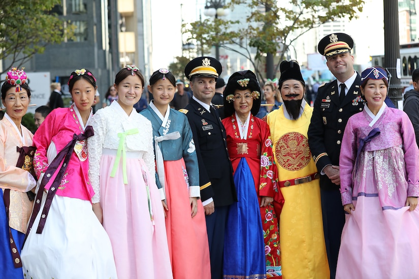 Korean Americans, dressed in traditional clothing, pause for a photo with Capt. Michael Ariola (center), Public Affairs Officer, 85th U.S. Army Reserve Support Command, Arlington Heights, Illinois, and Lt. Col. Arturo Napolitano (right), Commander, 318th Theater Public Affairs Support Element (TPASE) Arlington Heights, Illinois, before the start of Chicago’s 70th Annual Columbus Day Parade in the loop on Monday, October 10, 2022.