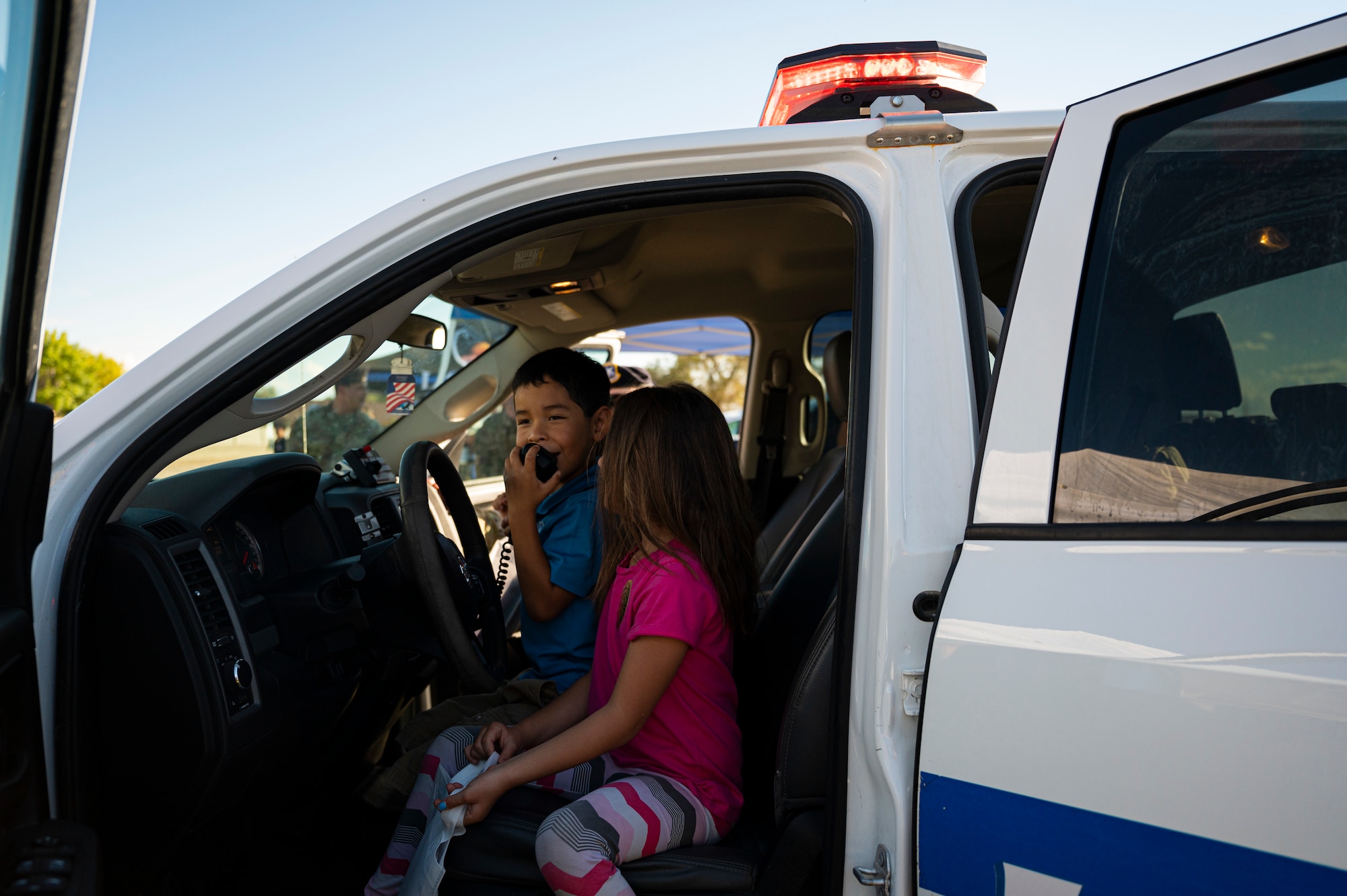 Children from Soaring Heights play with a loudspeaker in a 49th Security Forces Squadron patrol vehicle during the National Night Out event at Holloman Air Force Base, New Mexico, Oct. 4, 2022. The event brought together base and local law enforcement agencies to provide information on their respective organizations and child safety. (U.S. Air Force photo by Airman 1st Class Isaiah Pedrazzini)