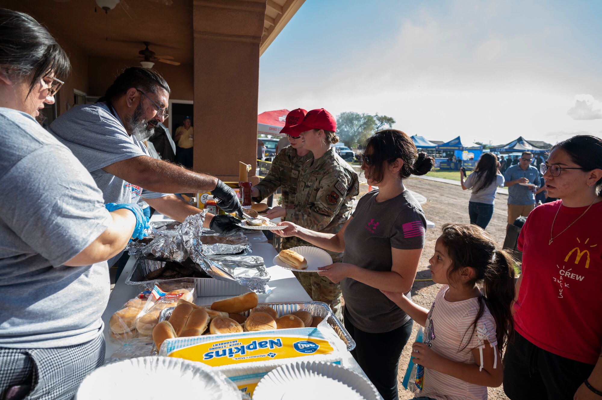 Soaring Heights community employees serve food to attendees of the National Night Out event at Holloman Air Force Base, New Mexico, Oct. 4, 2022. The community-based educational event was organized in order to strengthen the relationship between law enforcement departments and local community members. (U.S. Air Force photo by Airman 1st Class Isaiah Pedrazzini)
