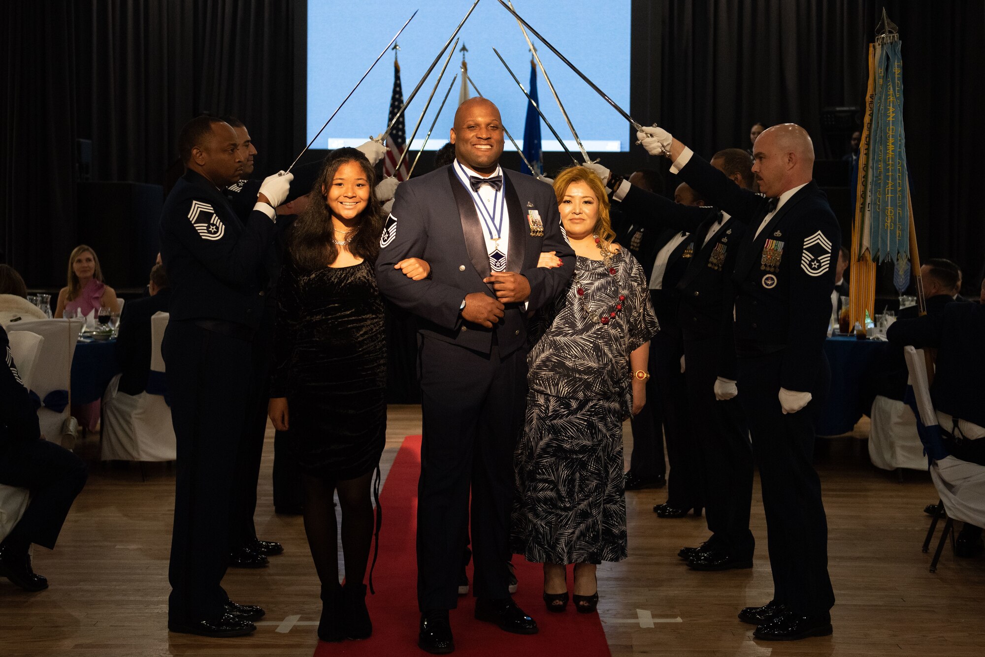 Master Sgt. Jay Brown, 51st Logistics Readiness Squadron aircraft parts store section chief, walks through a saber archway with his family during a Senior Non-Commissioned Officer Induction Ceremony at Osan Air Base, Republic of Korea, Oct. 6, 2022.