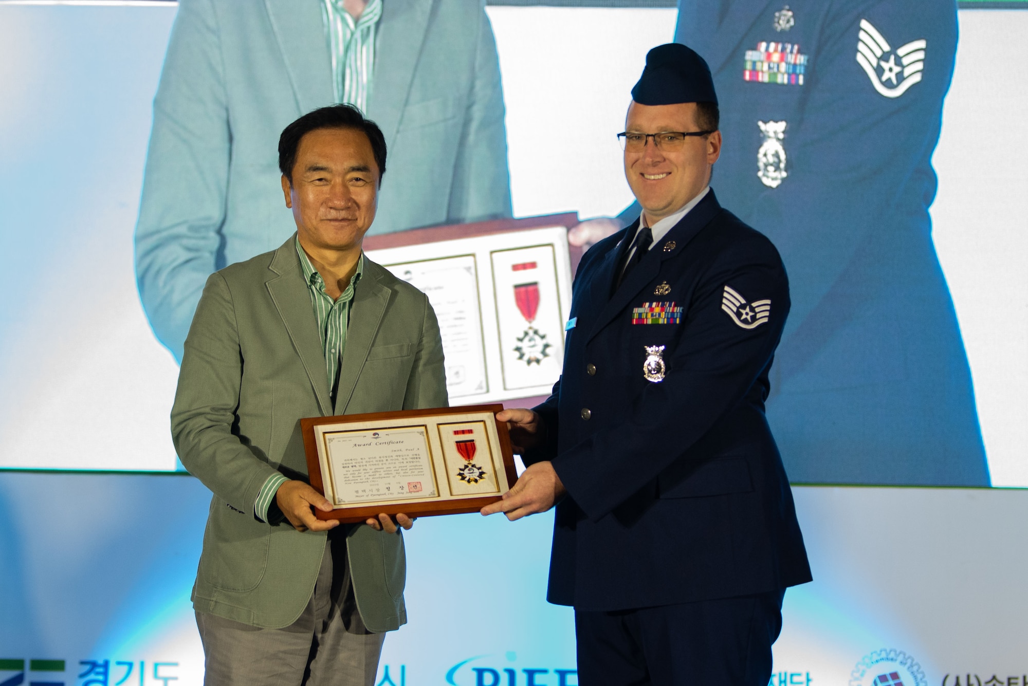 Jang Seon Jung, Pyeongtaek City mayor, presents a certificate of commendation to Staff. Sgt. Paul Smith, 51st Civil Engineer Squadron fire department NCO in charge of logistics, during the 19th Republic of Korea and the United States Cultural Festival, in front of Osan Air Base, Republic of Korea, Oct. 8, 2022.